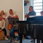 Bild von Schüler:innen beim Musizieren, im Vordergrund ein Flügel.