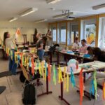 Bild mit Schüler:innen beim Basteln, im Vodergrund bunte Girlanden