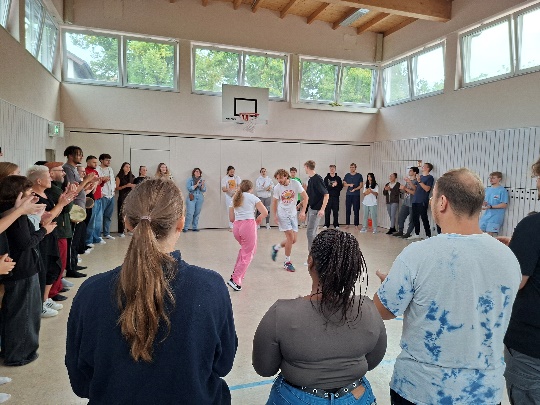 Die Auszubildenden stehen am Rand der Halle und in der Mitte wird etwas vorgeführt