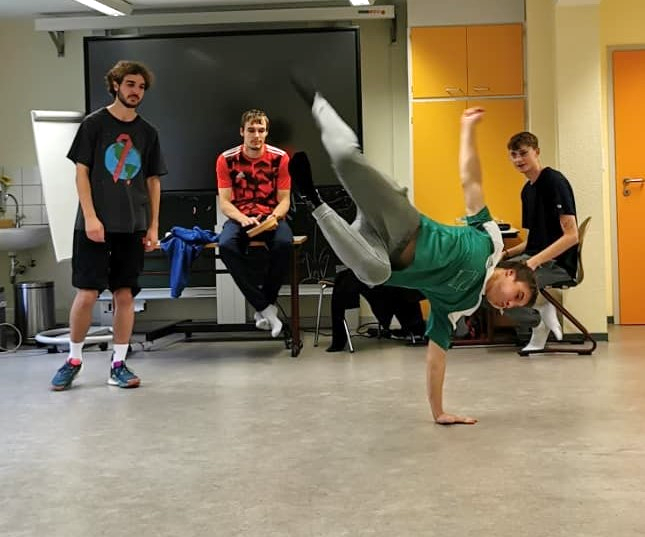 Drei junge Männer schauen zu, wie ein vierter Turnkunstsücke zeigt